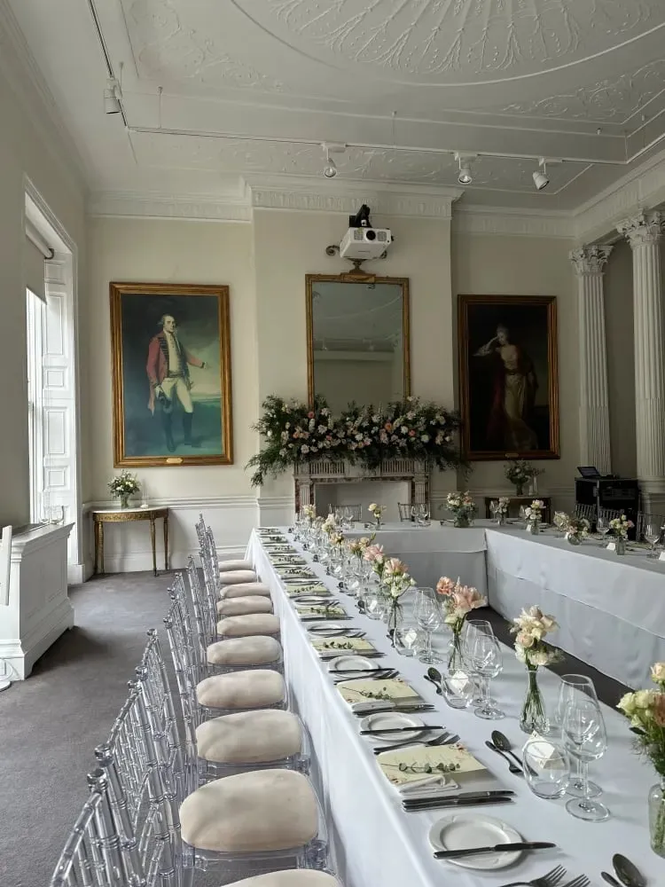 Long banquet table styled with white linen and low floral arrangements
