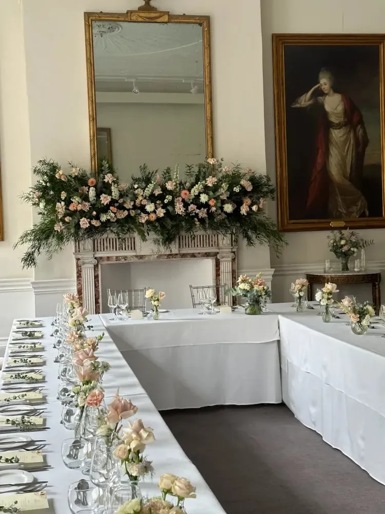 Mantelpiece garland of foliage and blush roses beneath a gilt mirror